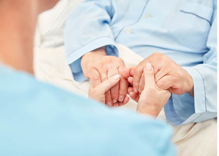 Nurse holding hands of patient in hospice care