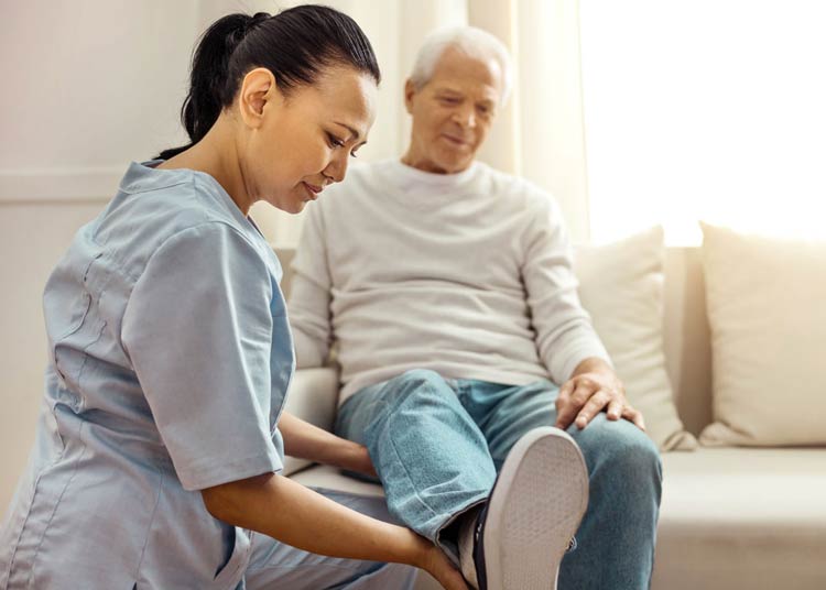 Nurse helps elderly patient with physical therapy