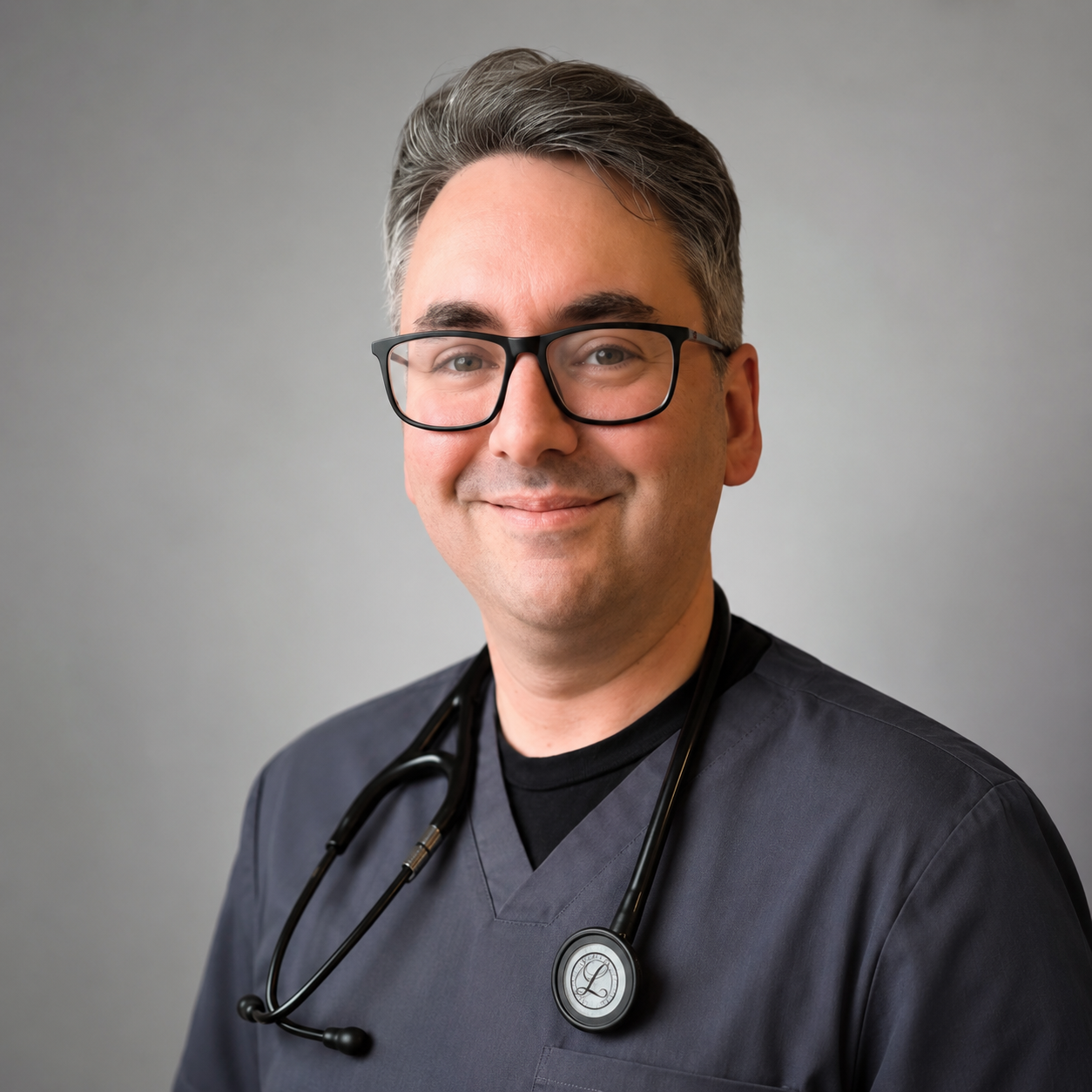Male nurse with silver brown hair black glasses and grey scrubs